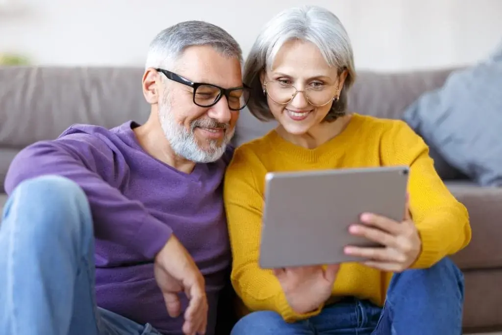 Mature couple looking at tablet with smile on face while watching a webinar